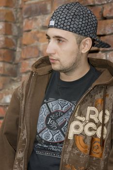 Rapper boy posing at a brick wall, urban scene