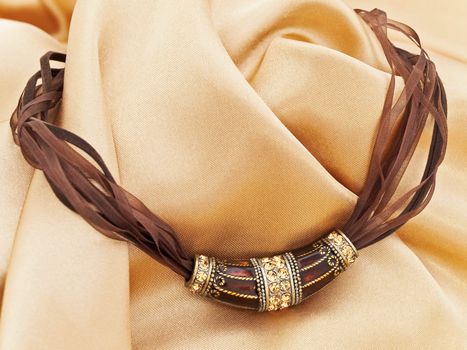  fashion brown necklace with gems over golden textile background