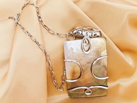  fashion necklace with metal decoration over golden textile background