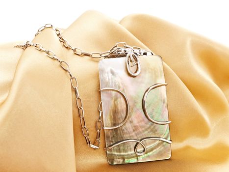  fashion necklace with metal decoration over golden textile background