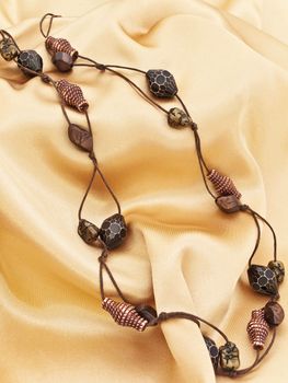  fashion wooden handmade necklace over golden textile background