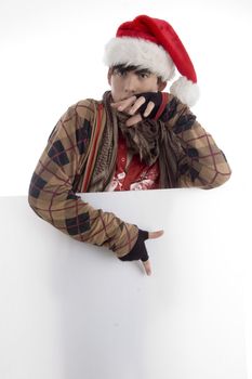 boy wearing christmas hat pointing placard against white background