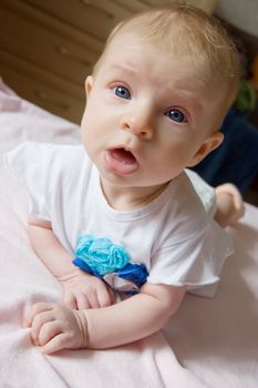 Funny baby lying on its belly on bed