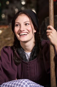 Beautiful farming girl sitting in the hay smiling