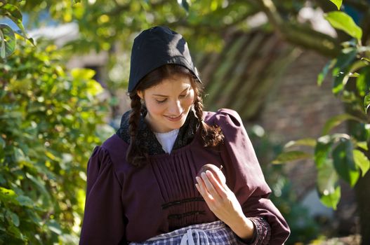 Pretty farmgirl checking the apple she just picked from the tree