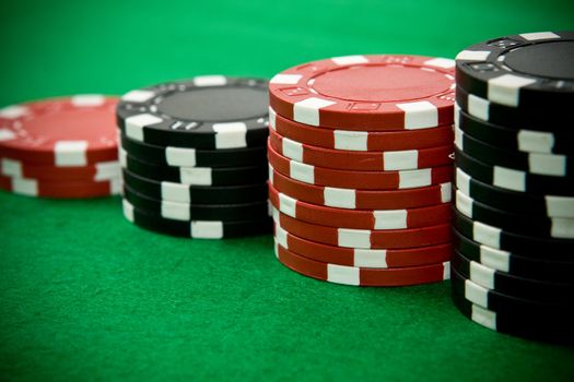 Stack of black and red poker chips on green table.