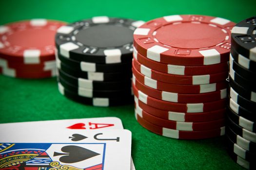 Ace of hearts and black jack with black and red poker chips in the background.