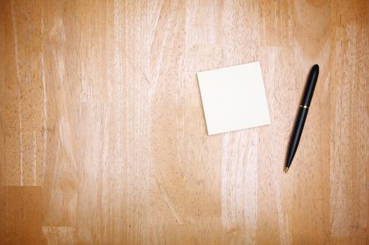 Pen and Post It Notes Pad Against a Wood Background
