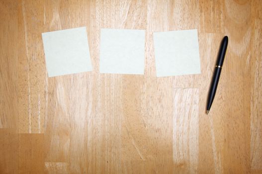 Pen and Post It Notes Pad Against a Wood Background