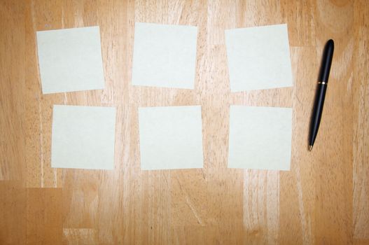 Pen and Post It Notes Pad Against a Wood Background