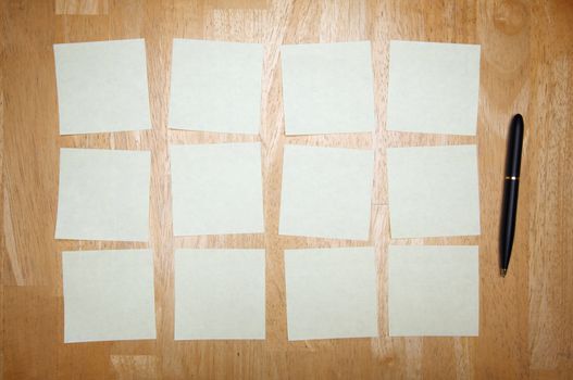 Pen and Post It Notes Pad Against a Wood Background