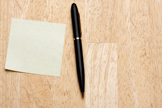 Pen and Post It Notes Pad Against a Wood Background