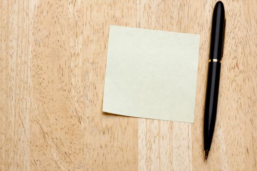 Pen and Post It Notes Pad Against a Wood Background