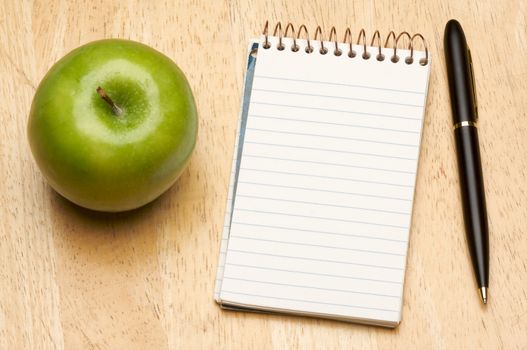 Pen, Paper and Apple on a Wood Background
