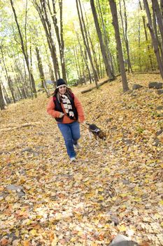 A young woman walking her dog through the woods.