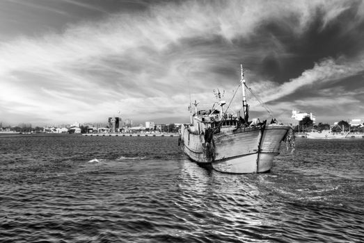 Dramatic landscape of harbor with one boat on water.