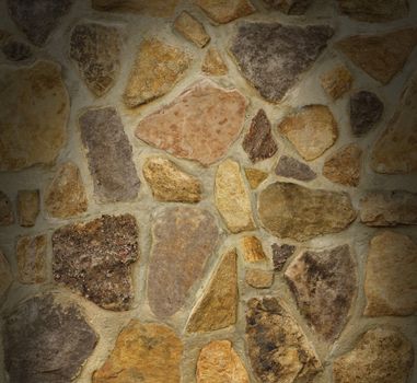 Masonry wall with irregular shaped stones dramatically lit from above