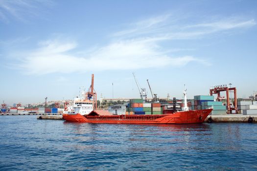 Sea panorama of container harbour with red vessel and cranes