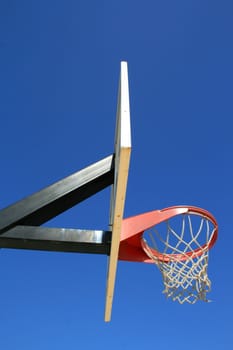 Basketball net and backboard over clear blue sky.
