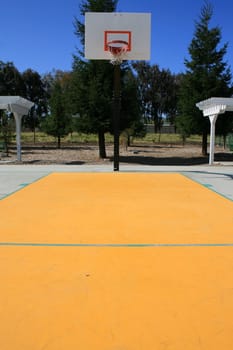 Basketball court on a sunny day in a park.
