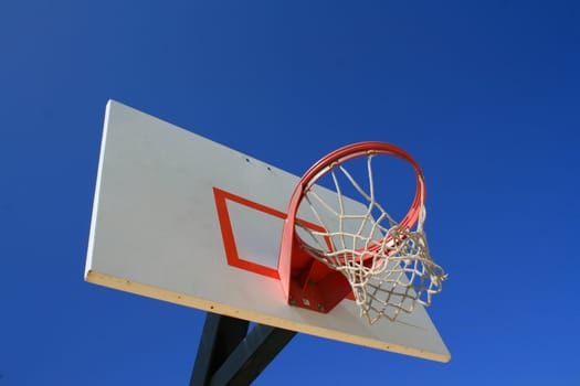 Basketball net and backboard over clear blue sky.
