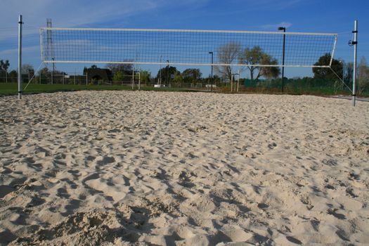 Beach volleyball court over bright blue sky.
