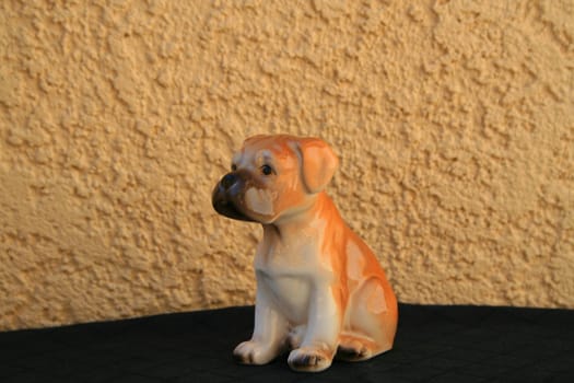 Small boxer puppy figurine over black and cream background.
