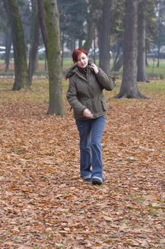 Redheaded backpacker girl walking in an autumn park.