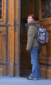 Young redheaded student opening the university doors.