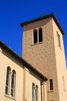 Tall mission style church in a city.
