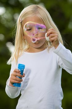 Cute four year old girl blowing a big soap bubble