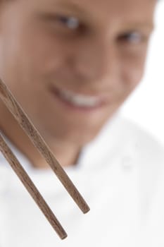 close up of chopsticks and chef in blur motion against white background
