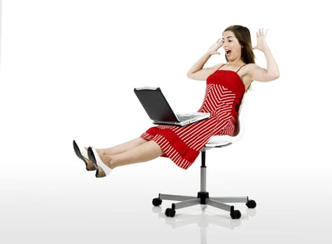 Portrait of a happy woman seated on a chair with a laptop - isolated on white