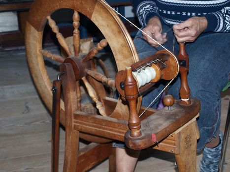 Antique vintage spinning wheel loom at work by a weaver