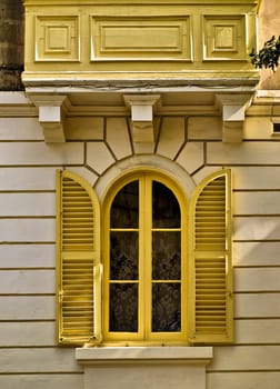 Yellow arched and louvered window of a house in Malta 