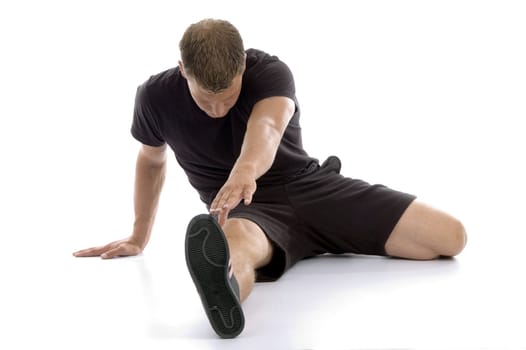 man stretching his legs against white background