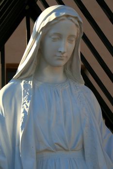 Statue of a Virgin Mary next to a church.
