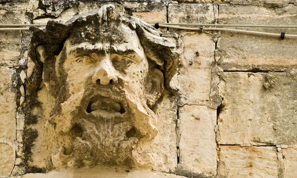 A medieval gargoyle face on a house in Malta