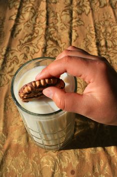 Close up of a cookie and a glass of milk.
