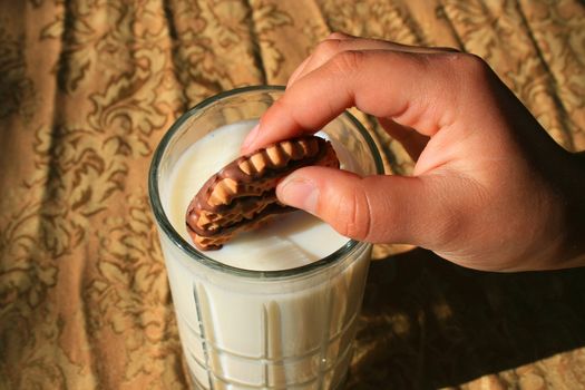 Close up of a cookie and a glass of milk.
