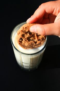 Close up of a cookie and a glass of milk.
