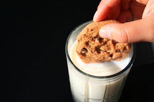 Close up of a cookie and a glass of milk.
