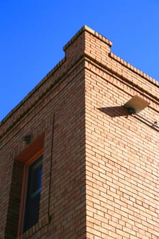 Corner of a brick building over blue sky.
