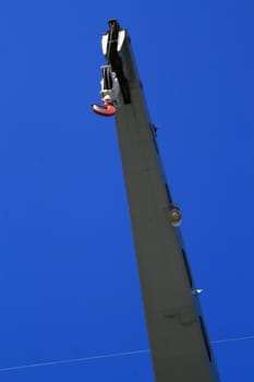 Industrial hook hanging over clear blue sky.
