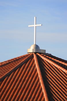 Cross on top of a church over blue sky.
