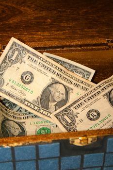 Close up of an antique box full of dollar bills.
