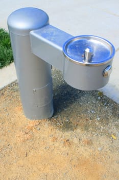 Drinking fountain on a sidewalk in a park.
