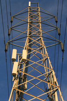 Top of the electricity pylon over blue sky.
