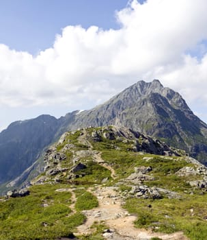 Narrow mountain path going up to a tall peak. Rauma, Norway