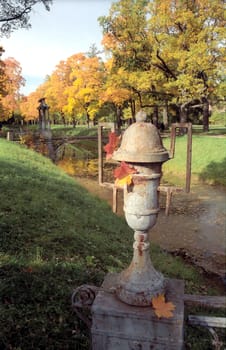 Old shabby metal vase in autumn park